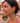 Woman wearing green heart-shaped earrings with a blurred background