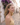 Woman with red earrings standing on a cobblestone street with purple flowers in the background