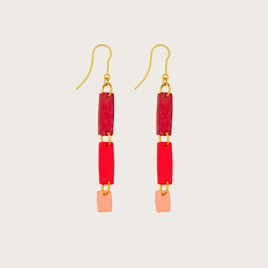 Pair of earrings with red and pink rectangular beads on a light gray background