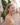 Woman standing on a cobblestone street with buildings and greenery in the background