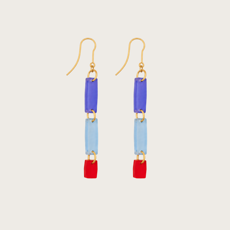 Colorful earrings with blue, red, and gold elements on a light gray background