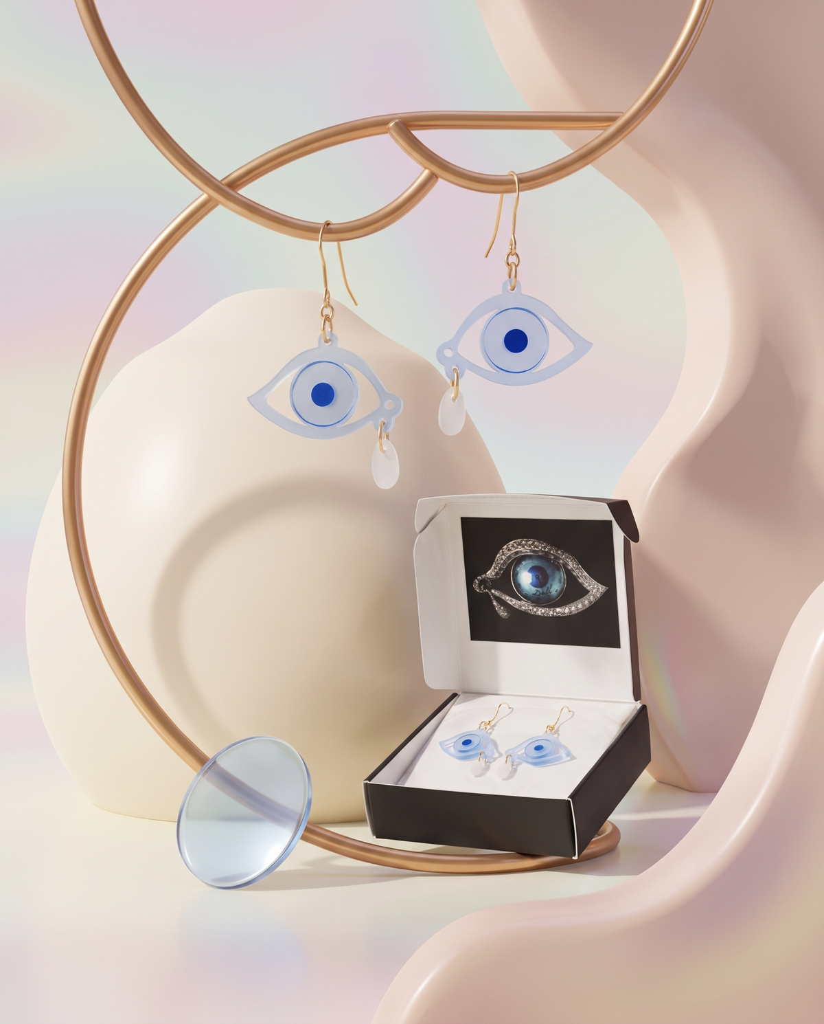 Pale blue Dream Eye acrylic earrings with tear detail displayed beside matching packaging in a soft pastel Materia Rica still life.