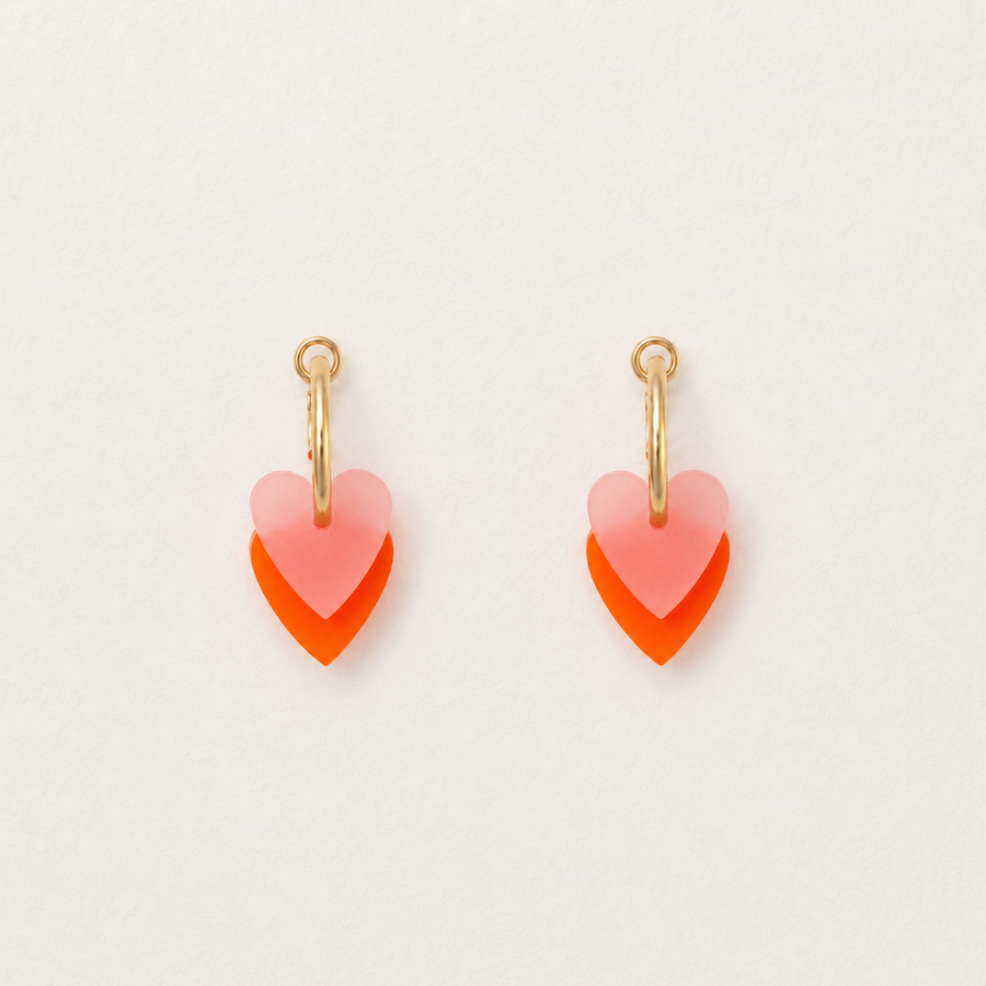 Heart-shaped earrings with pink and orange gradient on a light gray background
