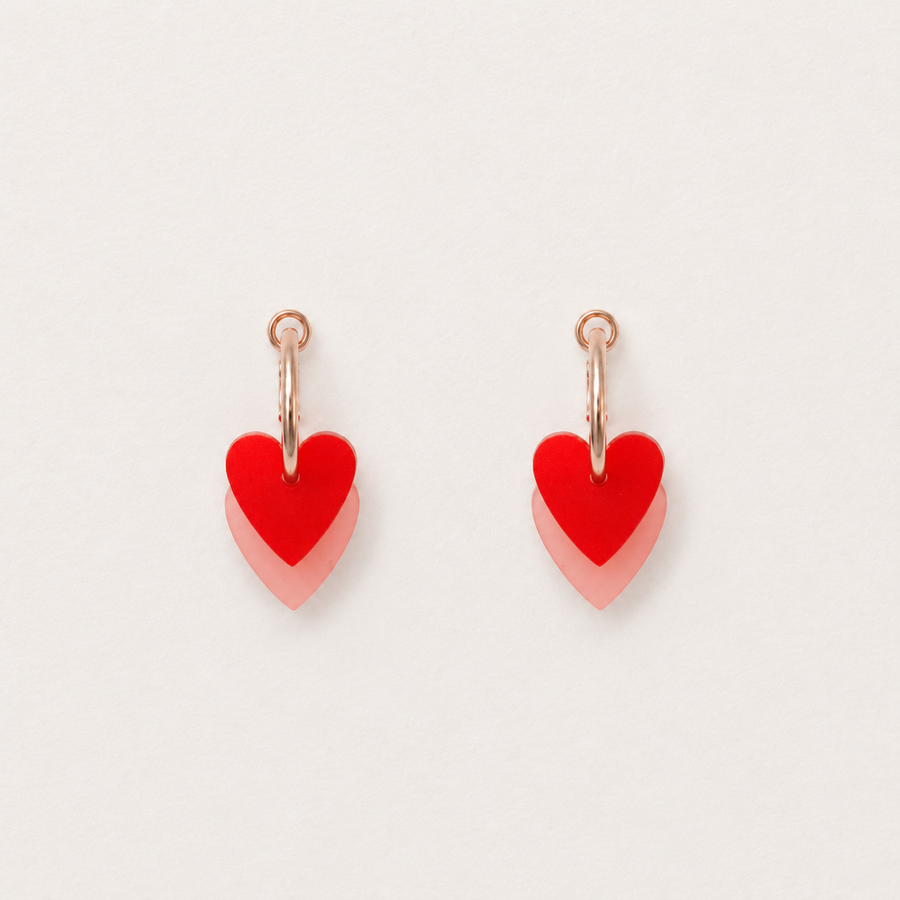 Red heart-shaped earrings on a light gray background