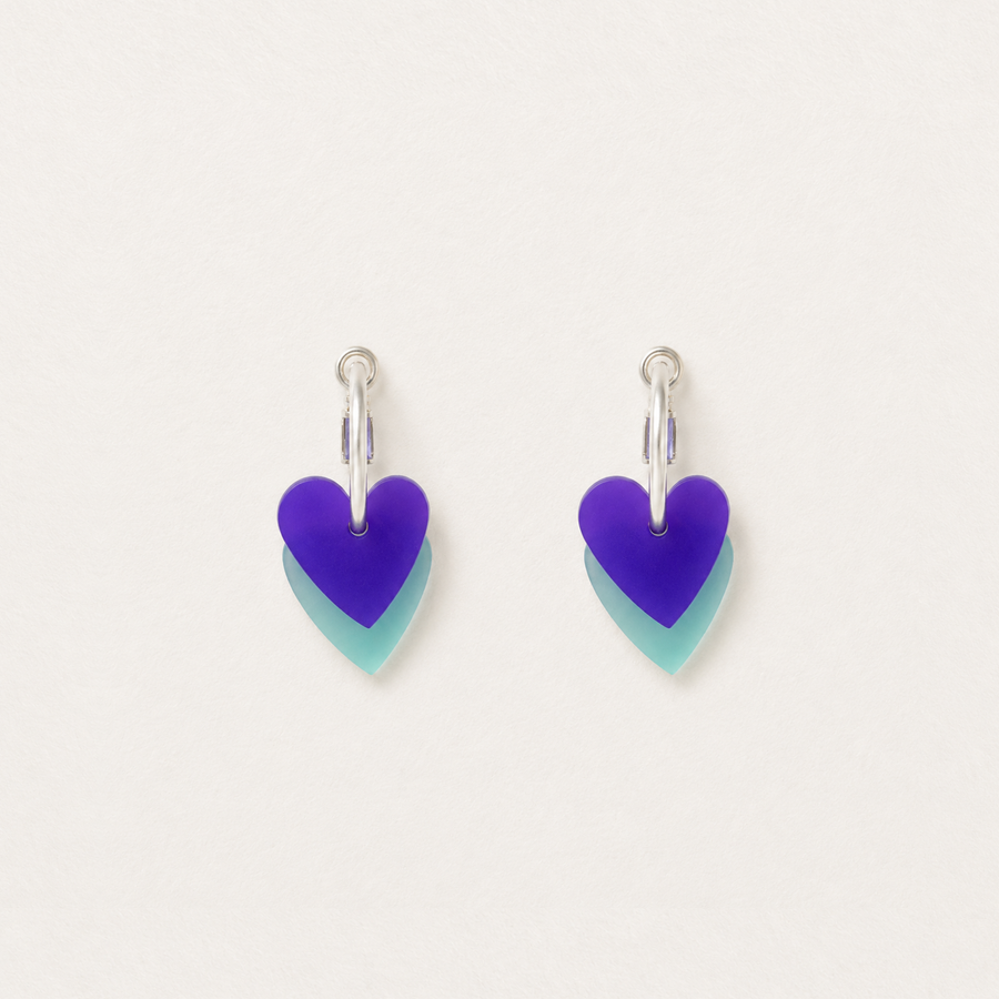 Heart-shaped earrings with purple and teal design on a light gray background