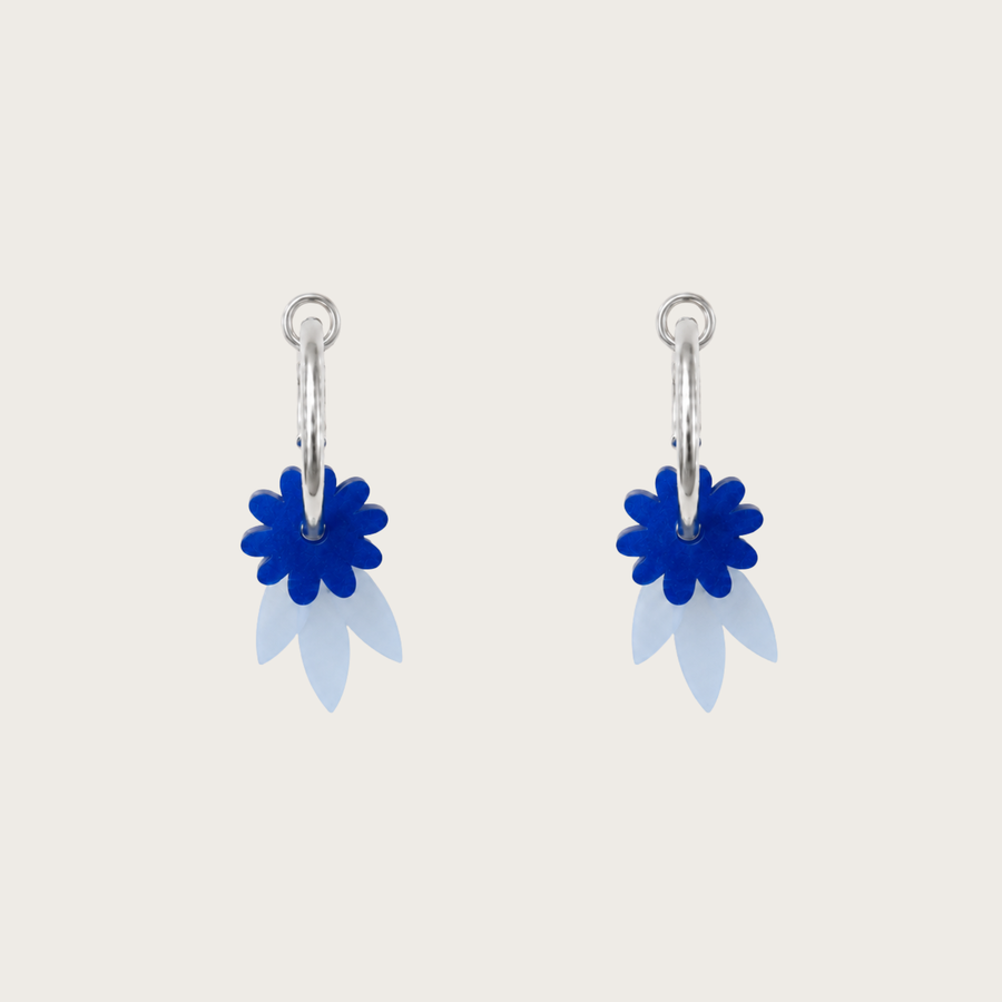 Pair of earrings with blue floral designs on a light gray background