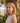 Woman with blonde hair standing in front of a stone wall and ocean view