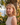 Woman with blonde hair standing in front of a stone wall and ocean view