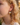 Close-up of a person wearing a floral earring with a blurred natural background