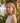 Woman with blonde hair standing outdoors with a scenic background