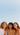 Three women standing together against a clear blue sky