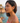 Woman wearing green earrings with a scenic background of water and rocks.
