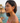 Woman wearing red earrings with a scenic background of water and rocks.