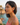 Woman wearing red earrings with a scenic background of water and rocks.