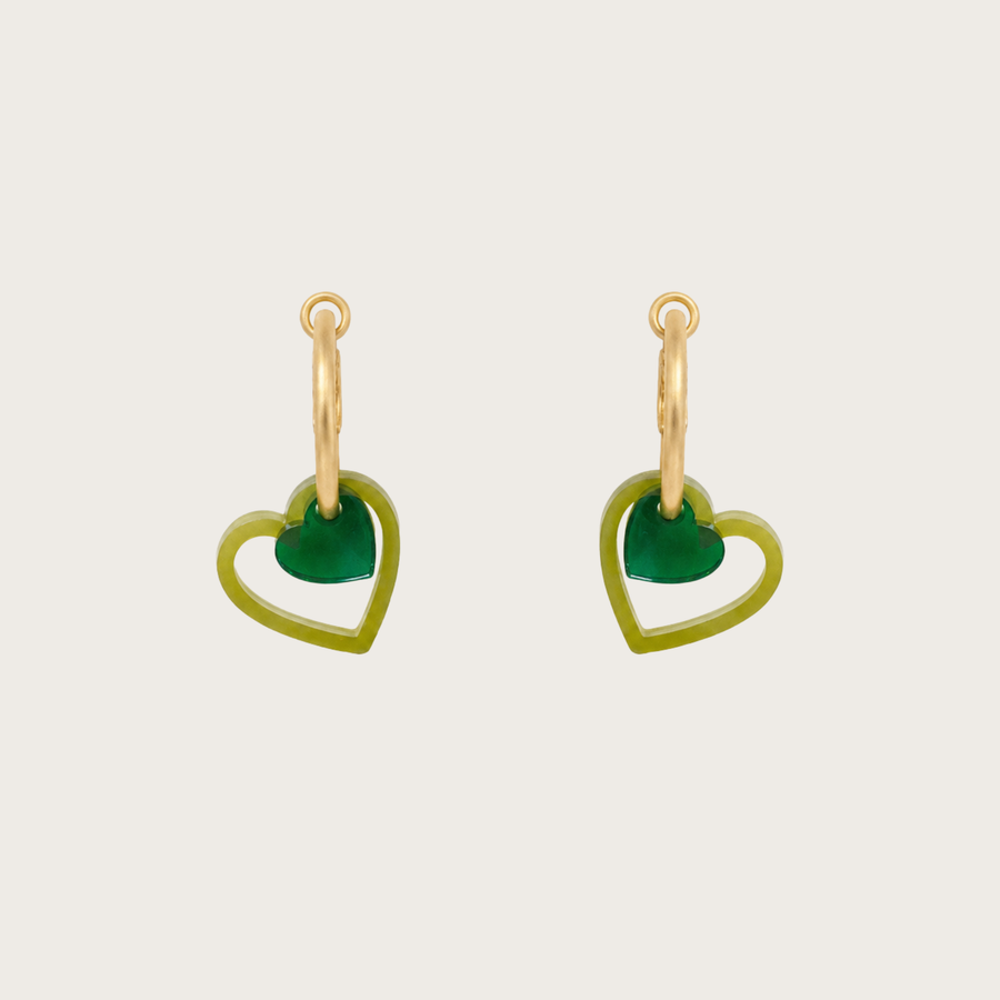 Heart-shaped green earrings with gold hooks on a light beige background