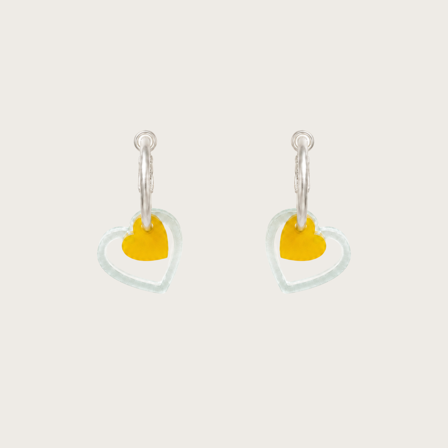 Heart-shaped earrings with yellow centers on a light gray background