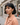 Woman with short black hair and a peach coat standing on a street.