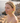 Woman wearing green earrings by a body of water with rocks.