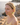 Woman wearing green earrings by a body of water with rocks.