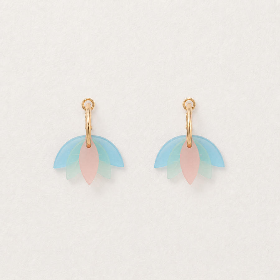 Pair of earrings with pastel-colored leaf-like charms on a light background