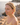 Woman with red earrings standing by a body of water with rocks.