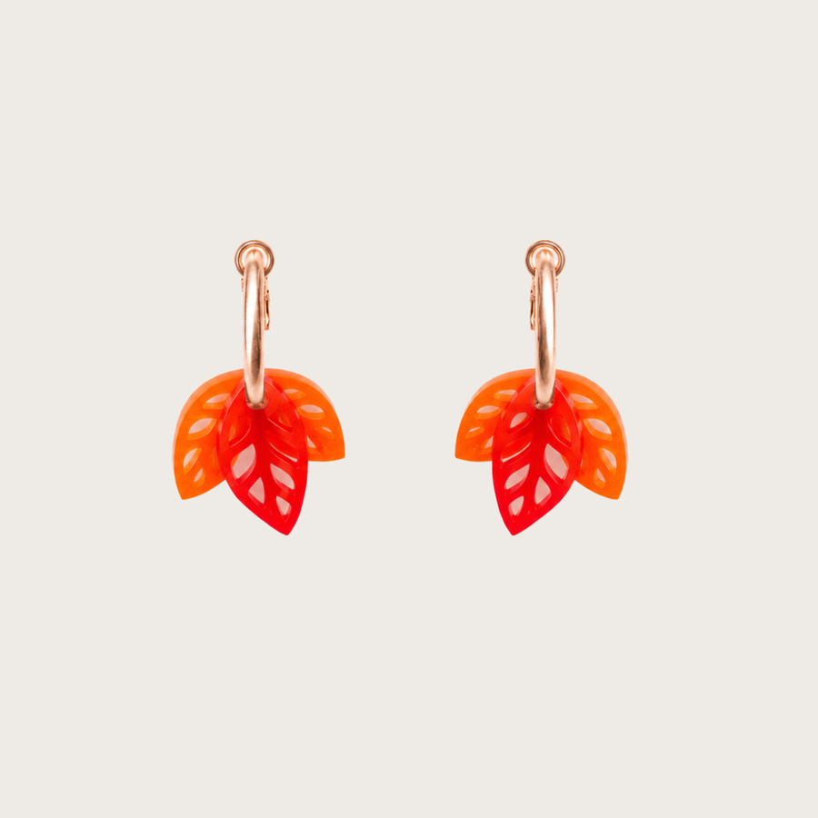 Pair of orange leaf-shaped earrings on a light gray background