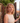 Woman with curly hair standing in front of a stone wall and wooden gate.